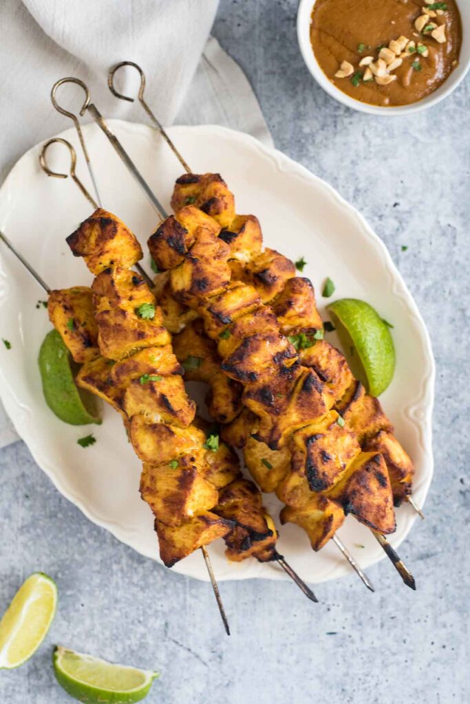 chicken satay skewers on platter with bowl of peanut sauce beside