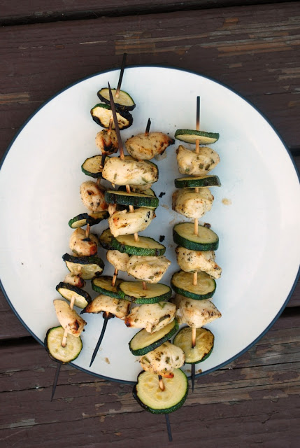a plate with skewers of chicken and zucchini on it