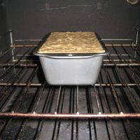 a bread tin in the oven filled with banana bread batter
