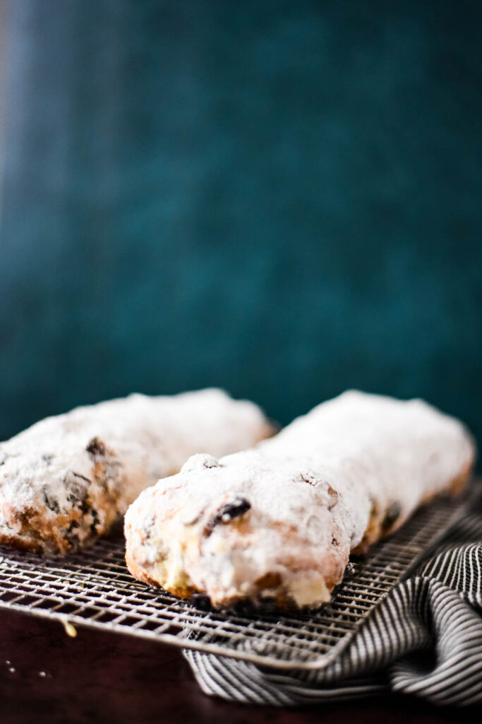 two freshly baked stollen loaves on wire rack coated with powdered sugar
