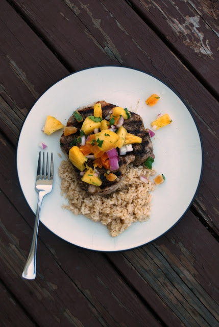 overhead view of brown rice with grilled pork chop topped with pineapple salsa