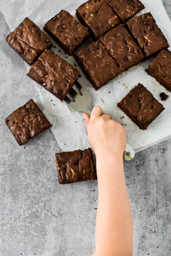 kids hand using spatula on zucchini brownies