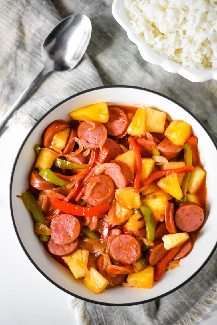 serving bowl filled with kielbasa, pineapple, and peppers with sauce