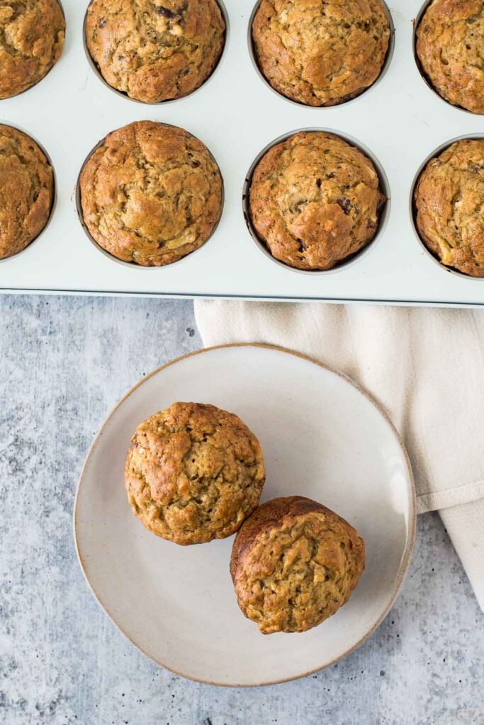 two muffins on a plate in front of muffin pan