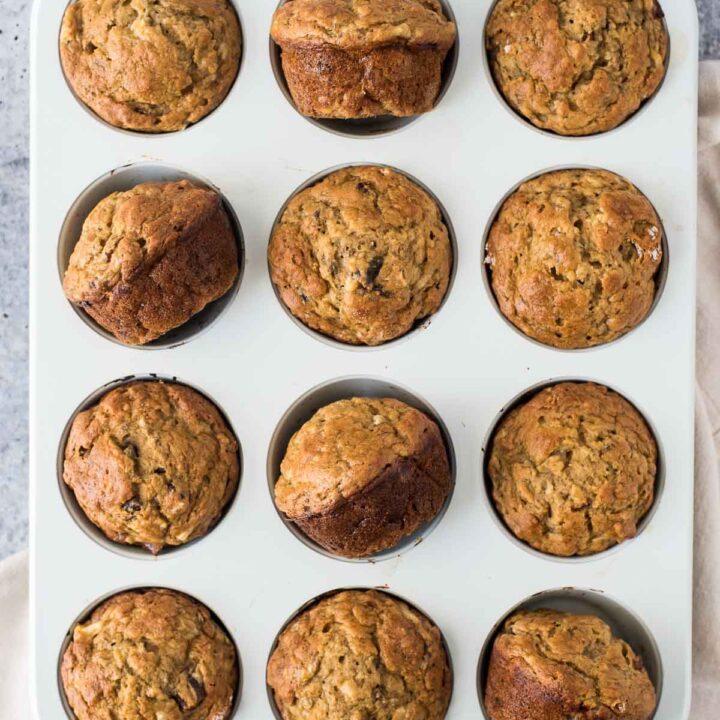 overhead view of white muffin pan with muffins, some of the muffins are pulled out and resting and odd angles in the muffin wells
