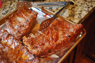 pork ribs on rimmed baking sheet with metal tongs