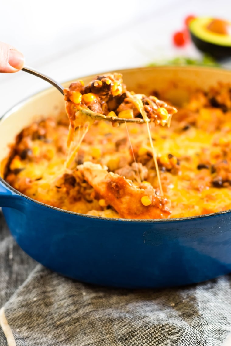 spoon pulling cheesy serving out of casserole dish