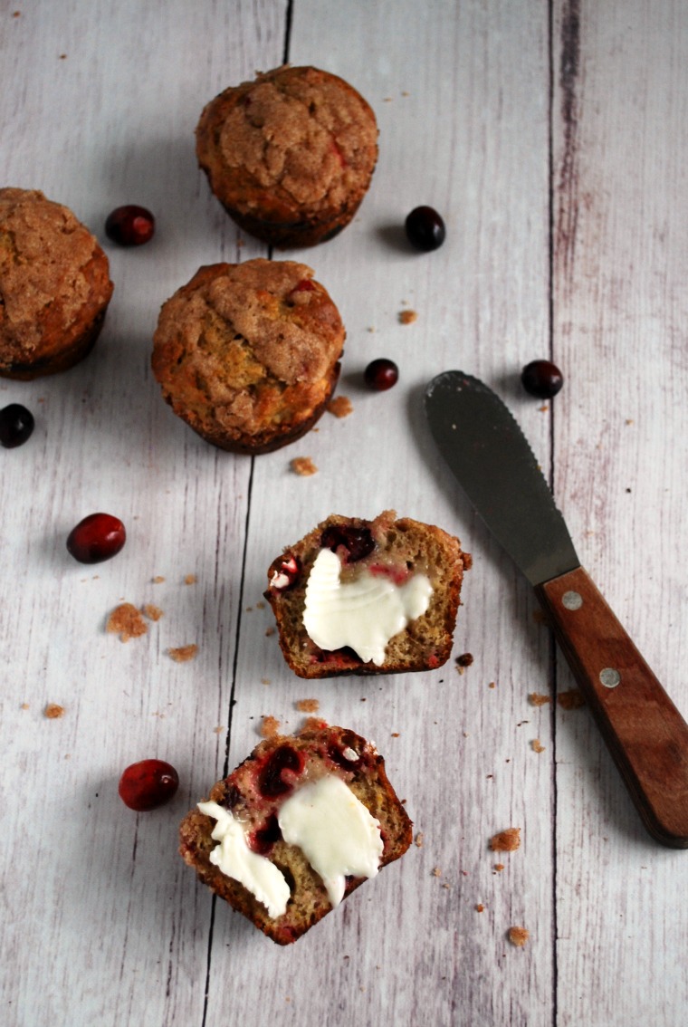 muffins on table, with one sliced open and slathered in butter