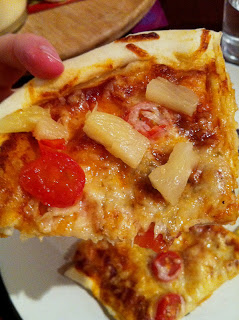 close up of pizza with cheese, tomato slices and pineapple pieces 