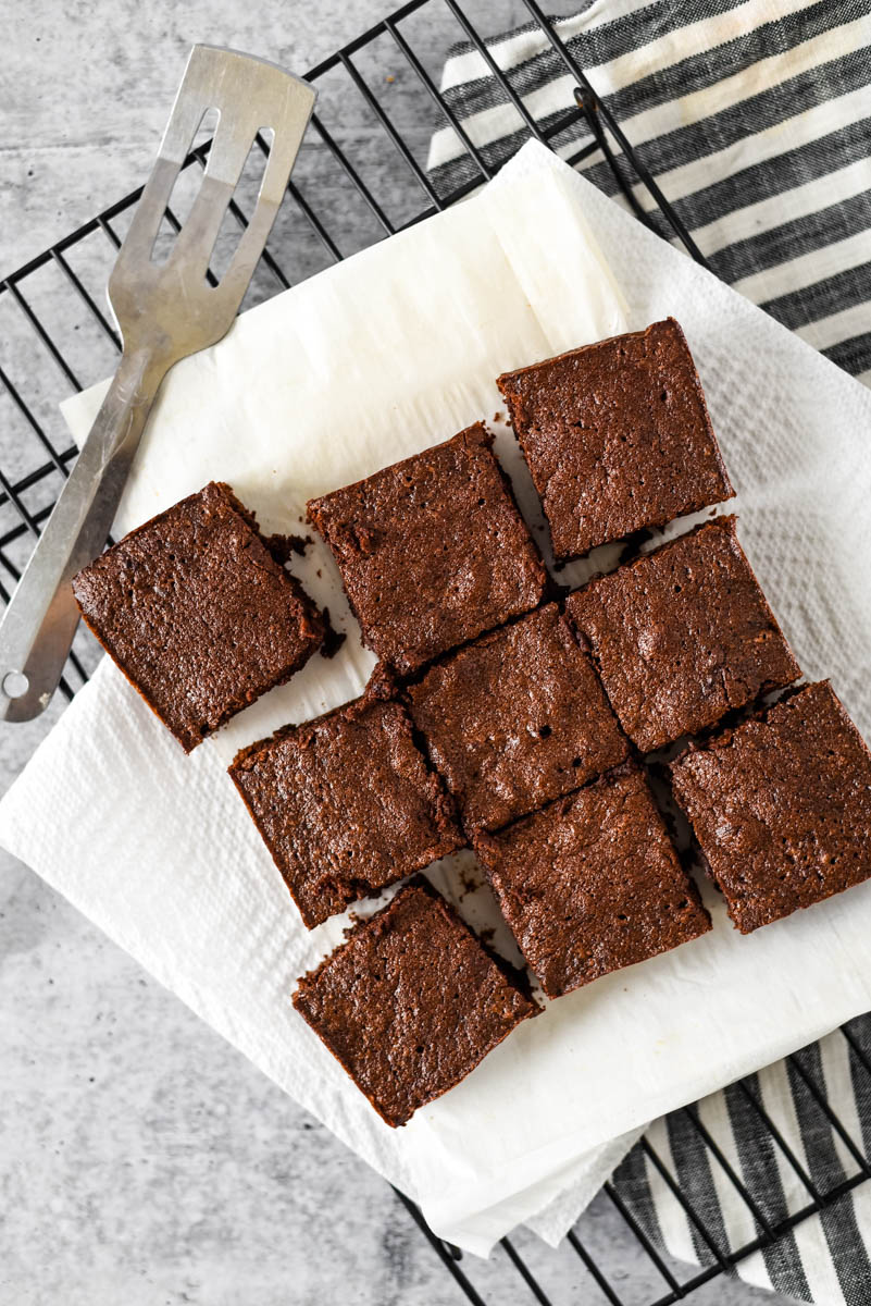 nine sourdough brownies on cooling rack with serving utensil