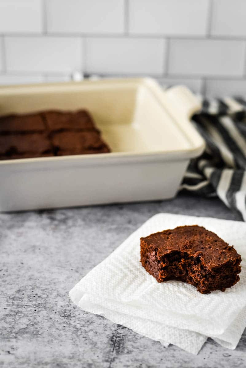 sourdough brownie with bite taken out in front of square pan with more brownies inside