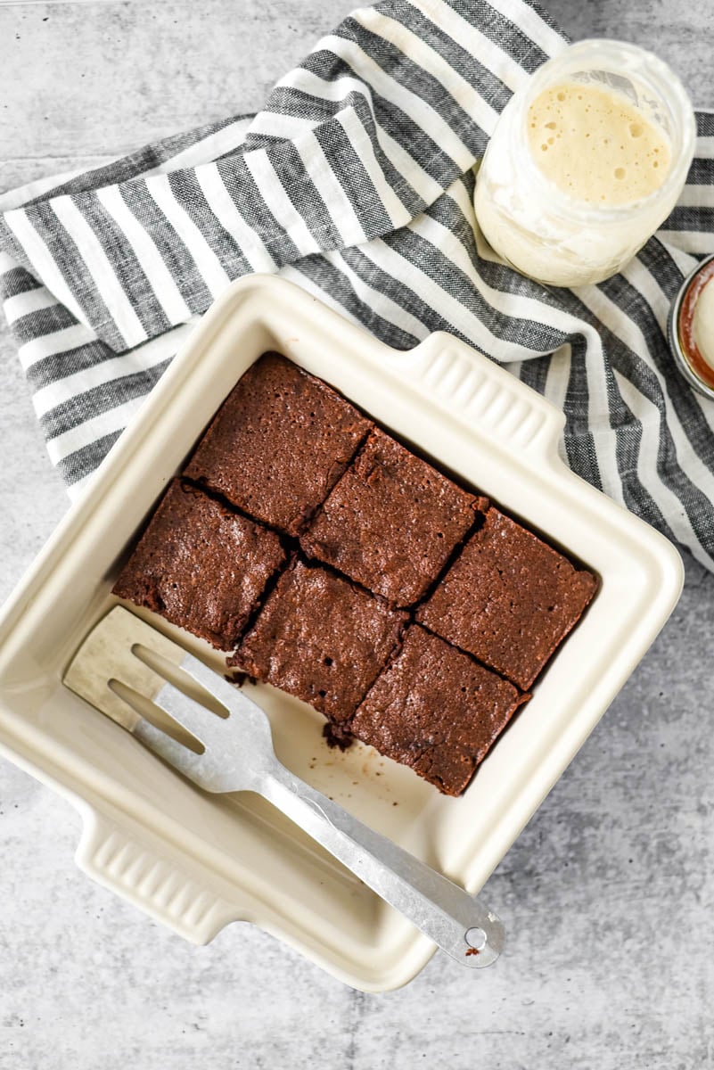 square baking pan with sourdough brownies next to jar of sourdough starter