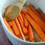 white baking dish with roasted carrot sticks and serving spoon