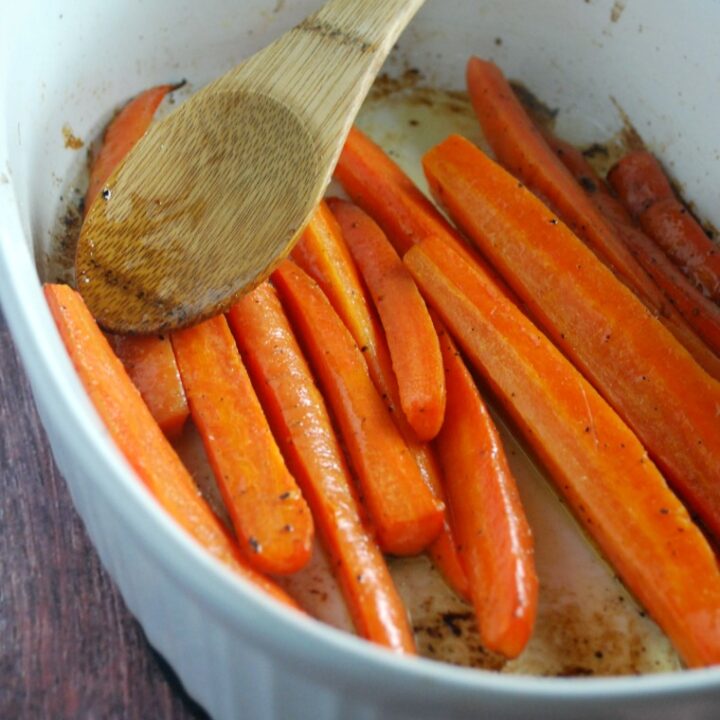 white baking dish with roasted carrot sticks and serving spoon