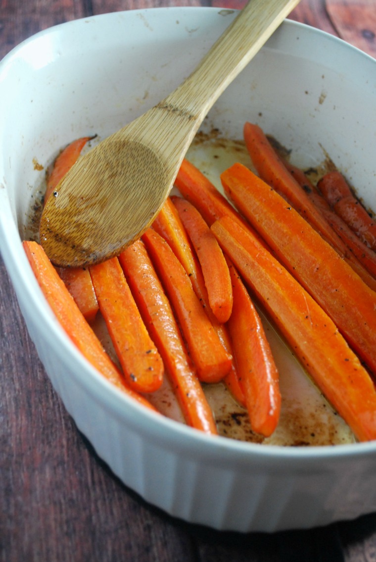 white baking dish with roasted carrot sticks and serving spoon