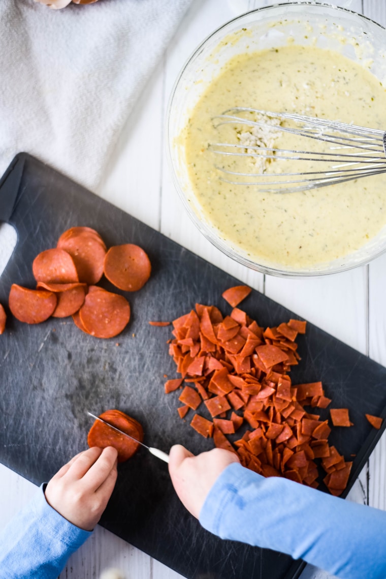 child cutting pepperoni for pizza bites