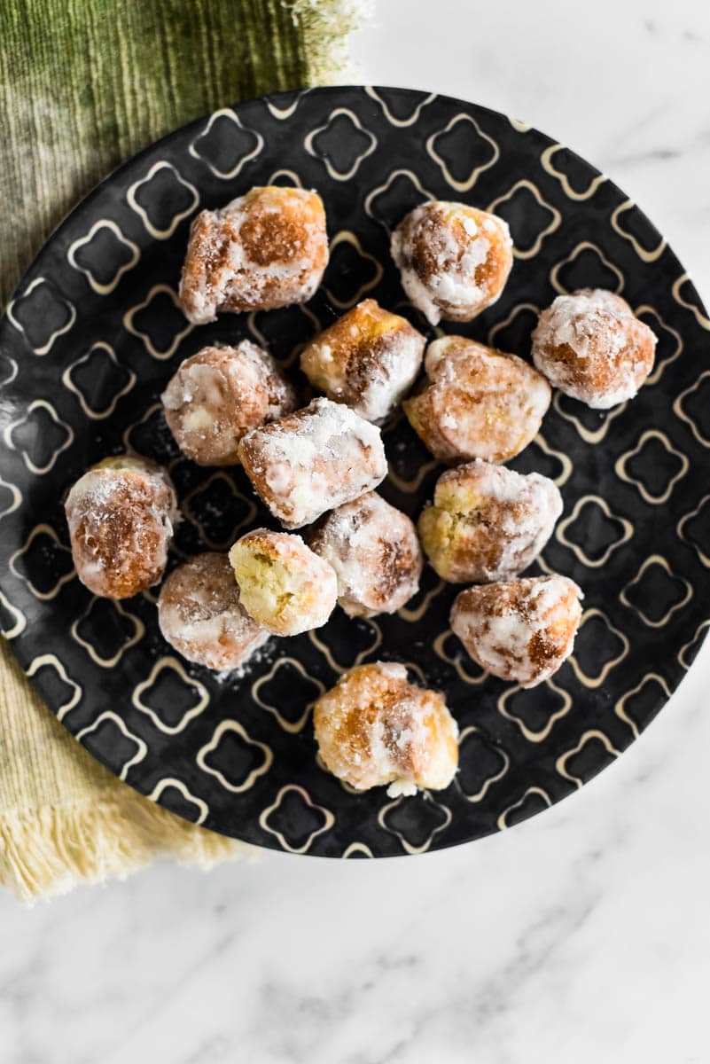 sourdough donut holes covered in powdered sugar on patterned plate