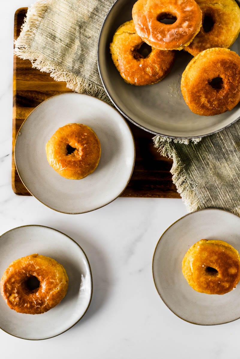 three sourdough donuts on small plates beside filled bowl