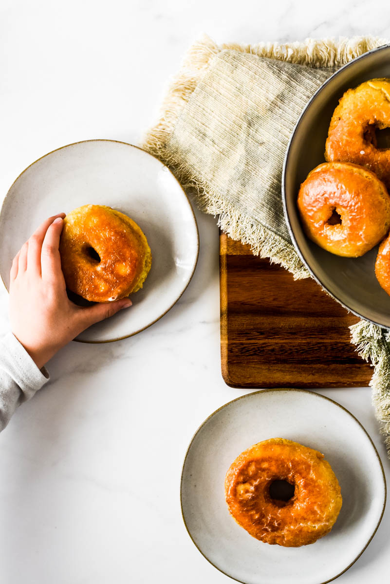 child's hand taking sourdough donut off of small plate