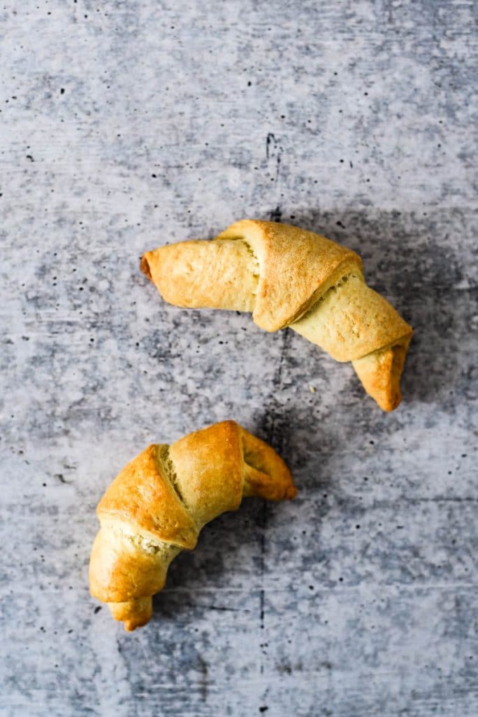 two sourdough crescent rolls on blue background