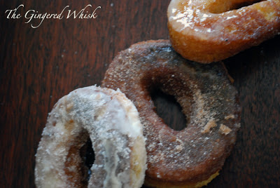 close up of three donuts with glaze, cinnamon sugar, and powdered sugar toppings