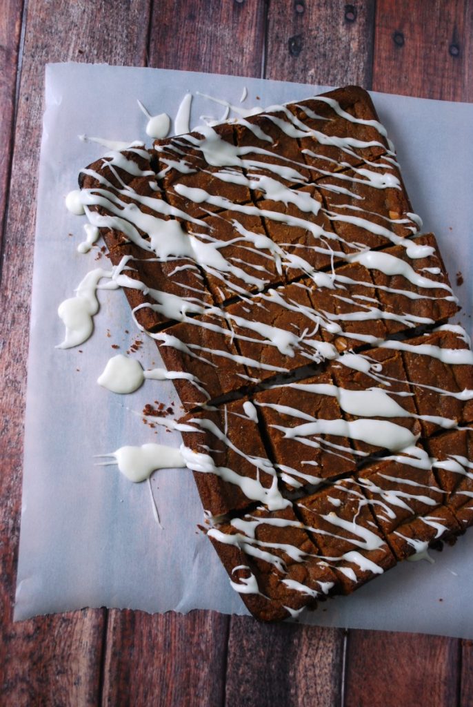 butterbeer bars on parchment paper with icing drizzled over 