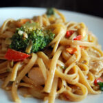 chicken pad thai on plate with red peppers and broccoli
