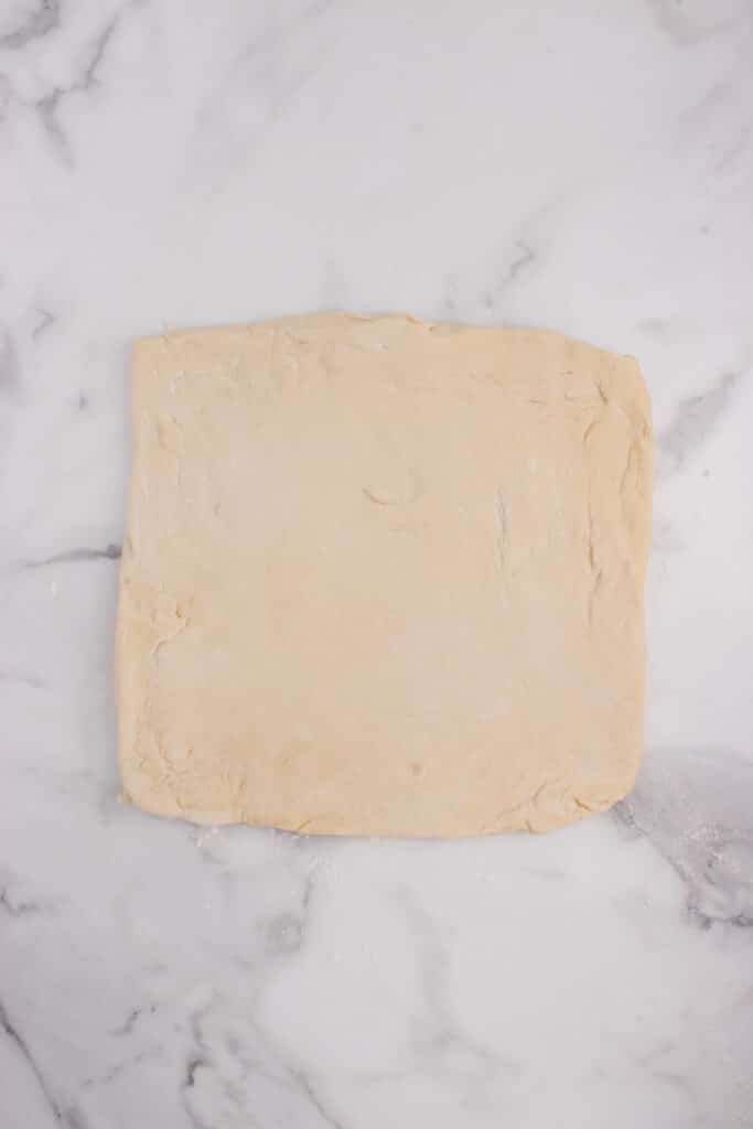 square of dough on marble counter