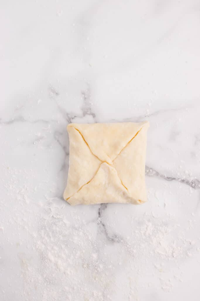 square of dough with corners folded into center