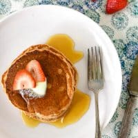 plate with strawberry pancakes with fork and napkin