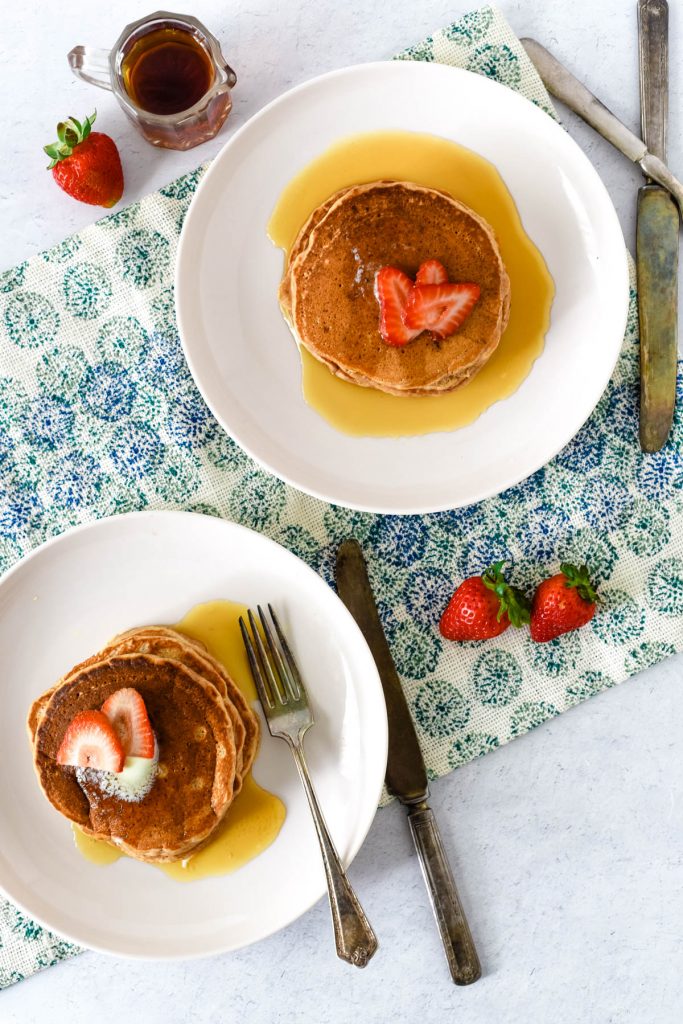 overhead of two plates with pancakes and strawberries