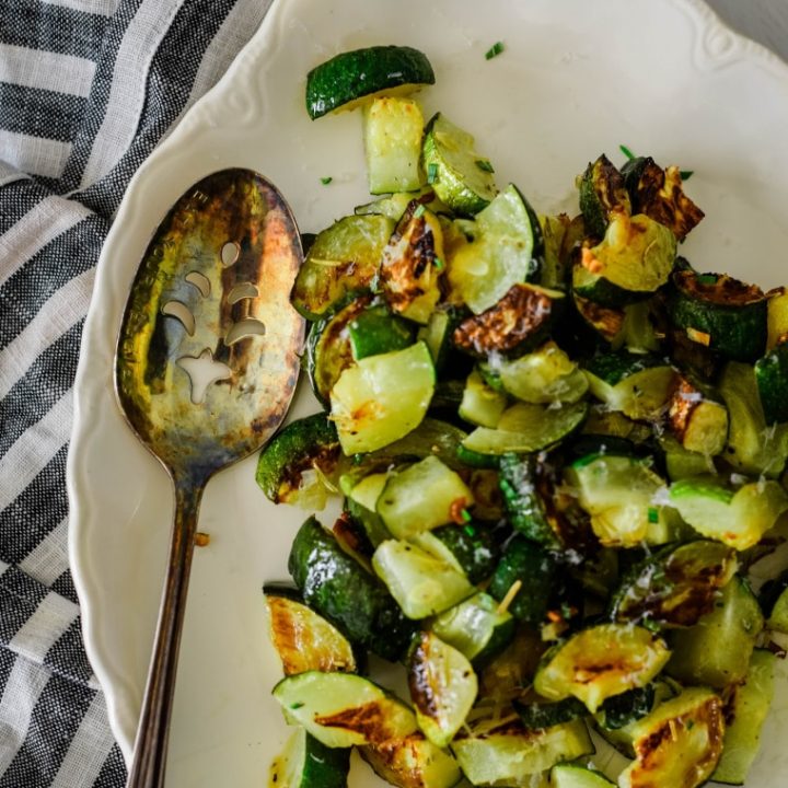 garlic baked zucchini on serving platter with spoon