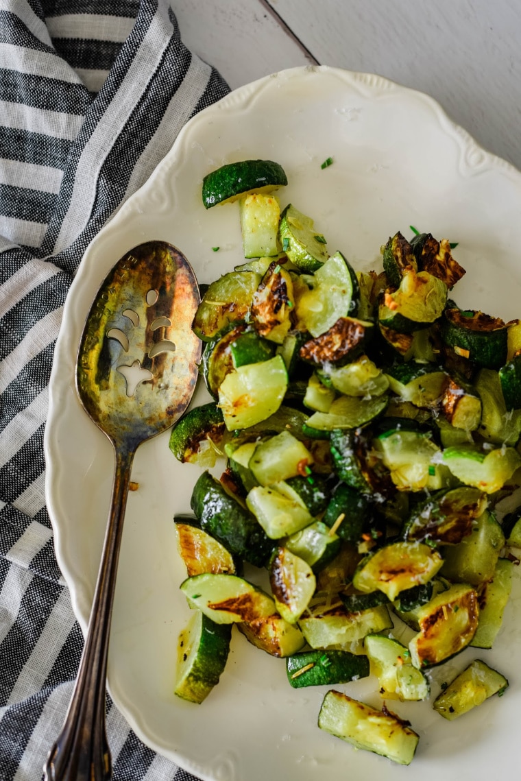 garlic baked zucchini on serving platter with spoon 