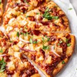 hawaiian bbq chicken pizza on counter with slices separated