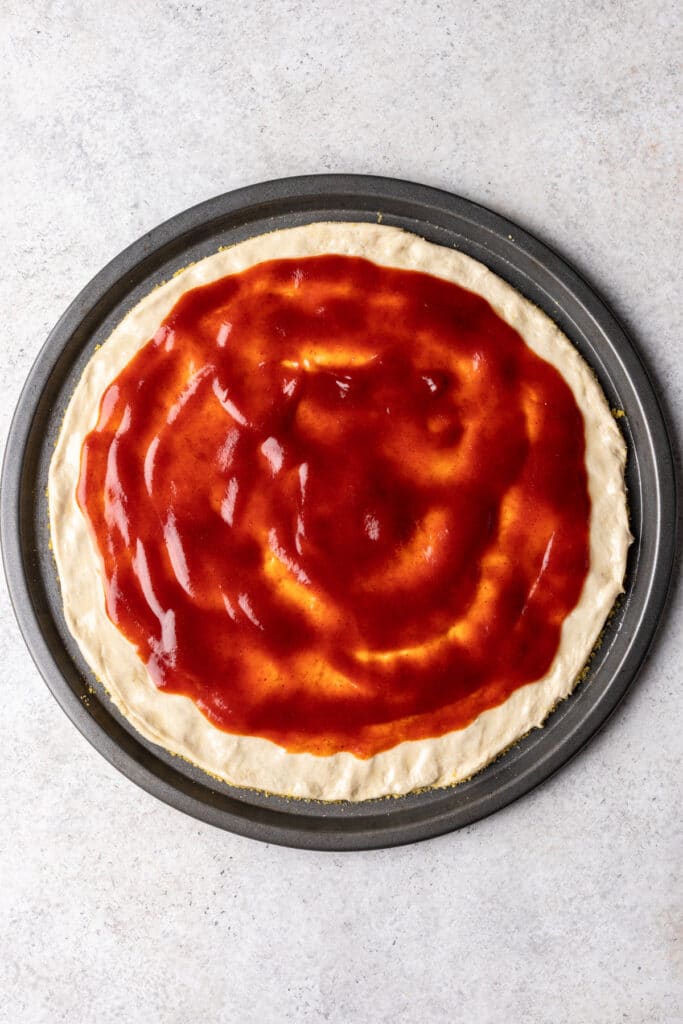 circle pan with pizza dough and sauce spread over