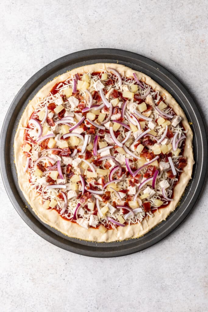 Hawaiian bbq chicken pizza on circle pan ready to be baked