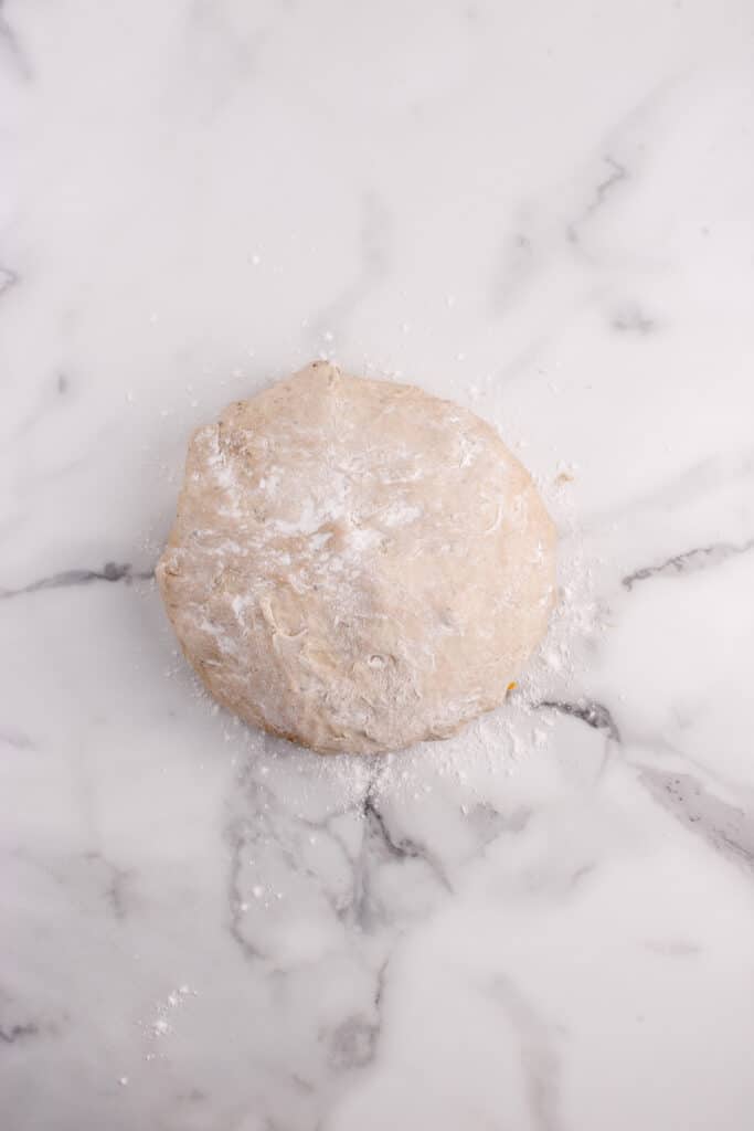 ball of dough on marble counter being shaped