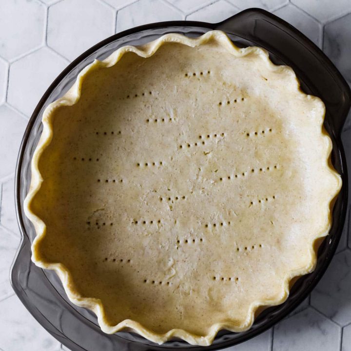 sourdough pie crust in grey glass pie plate on tiled background