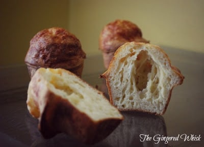 cheese sourdough popovers on table, with one split in half