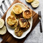 sourdough English muffins on white platter with fork beside