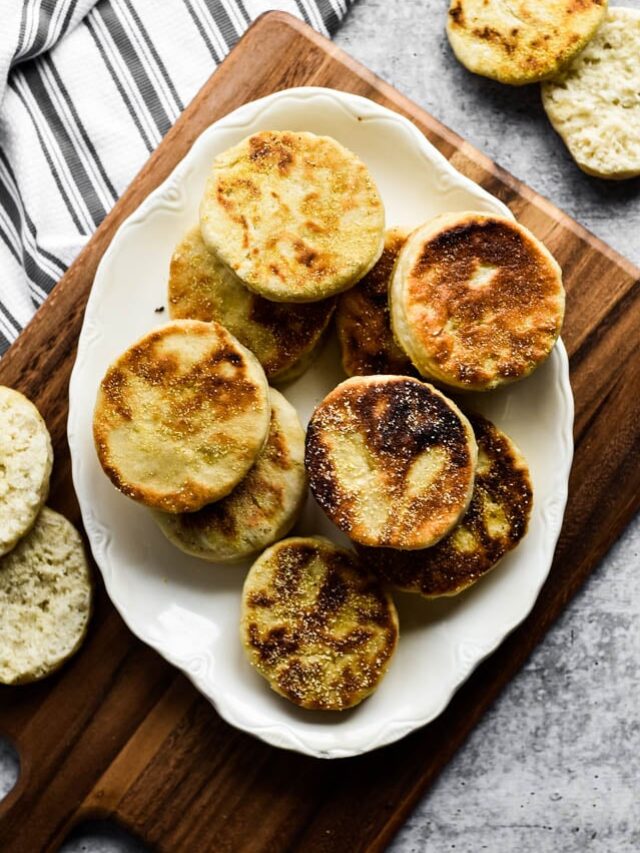 sourdough English muffins on white platter with fork beside