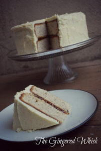 two layer earl grey cake with orange buttercream on cake stand with slice on plate in front