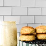 sourdough biscuits stacked on cooling rack beside jar of starter