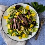 asian steak salad with mango on white plate