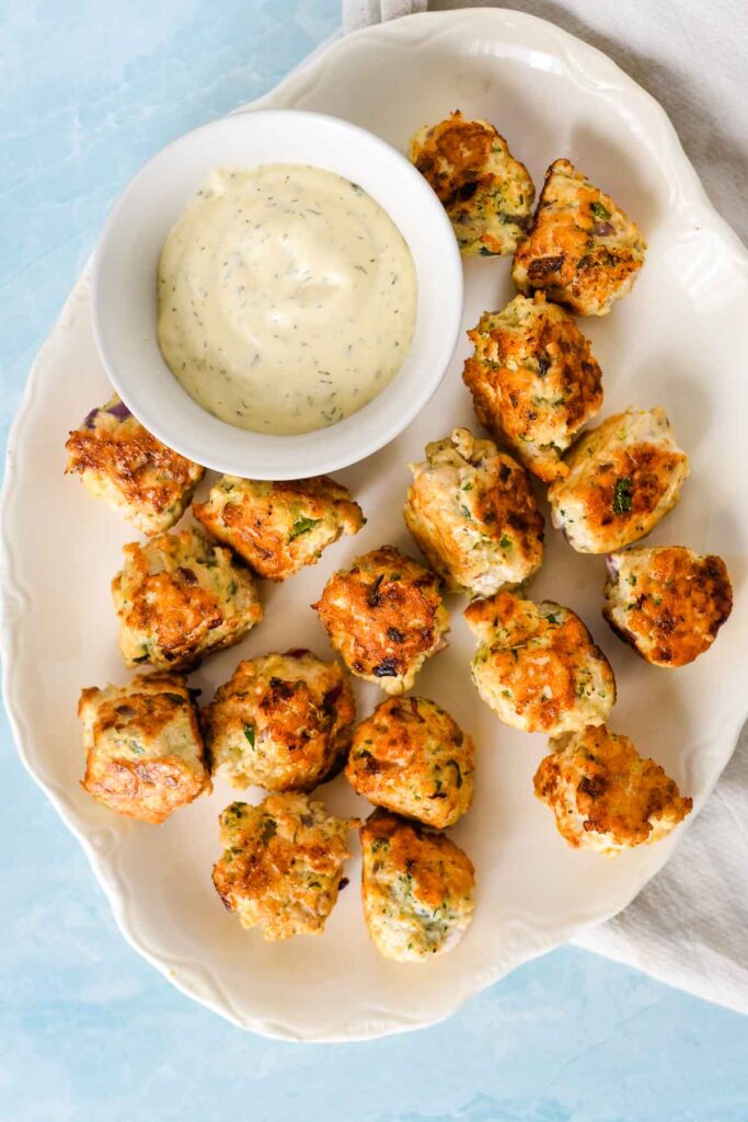 chicken meatballs on white platter with serving bowl of tzatziki sauce beside