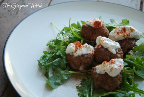 plate with greek meatballs on top of arugula