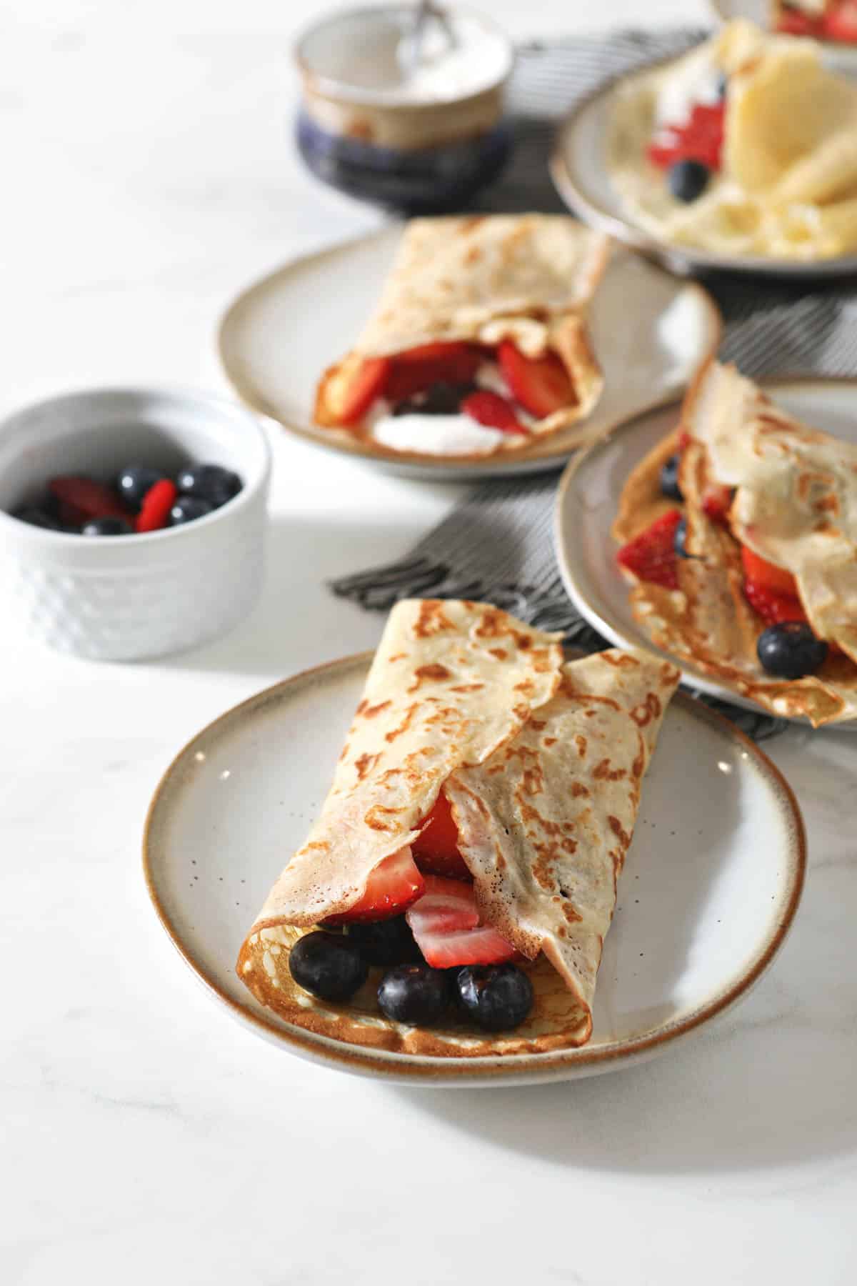 Sourdough Crepes on multiple plates with berries