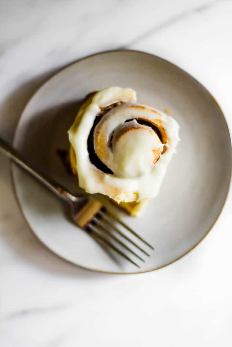 overhead view of one sourdough cinnamon roll on a plate with fork beside