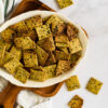 sourdough crackers scattered on white platter and table, resting on wooden cutting board