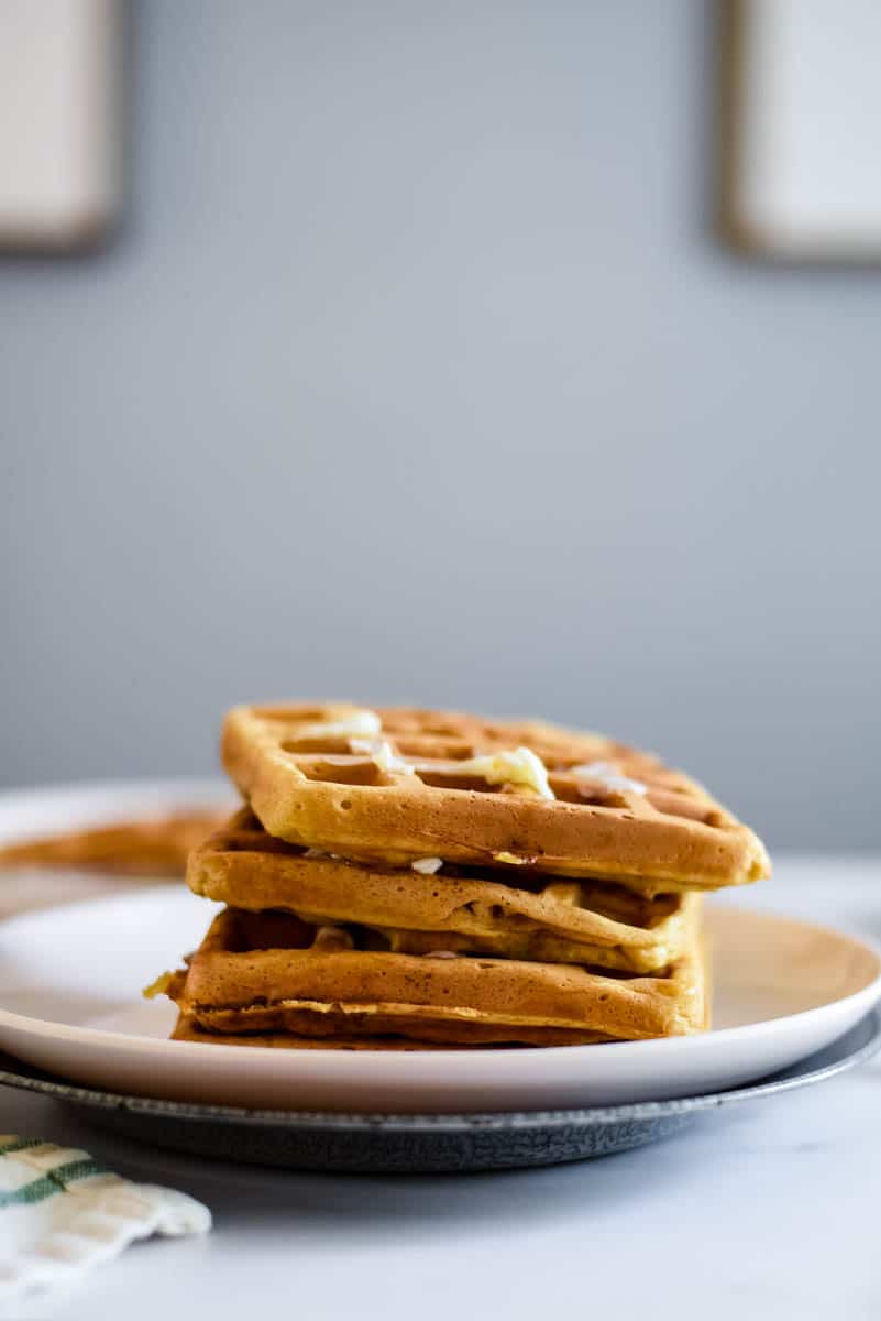 three sourdough waffles stacked on a white plate